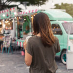 Young asian woman walking in the food truck market furing her pilgrimage to Seoul filming locations.