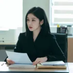 A woman lawyer si stiting behind her desk with a piece of paper in her hand. form the Good Partner Korean Drama