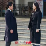 A man and a woman in dark winter coats are standing opposite to each other.