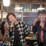 A man and a woman singing Karaoke in a bar with friends. From the Korean Drama My mister