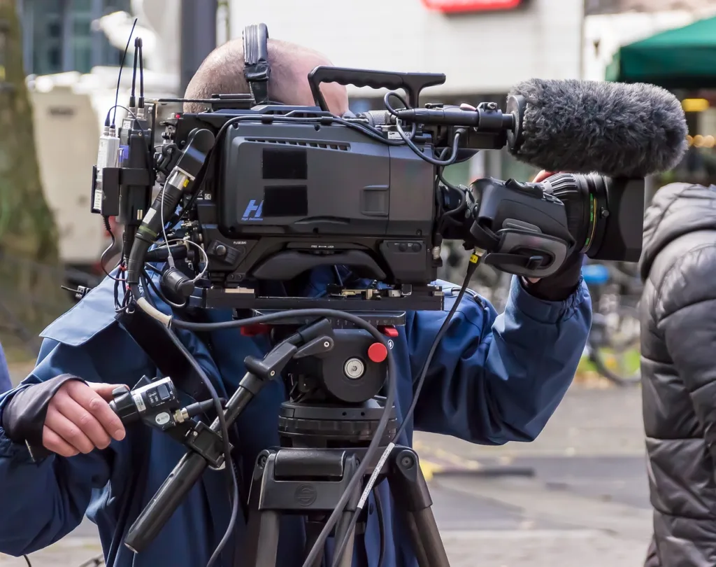 A cameraman with a huge camera shooting a Korean drama.