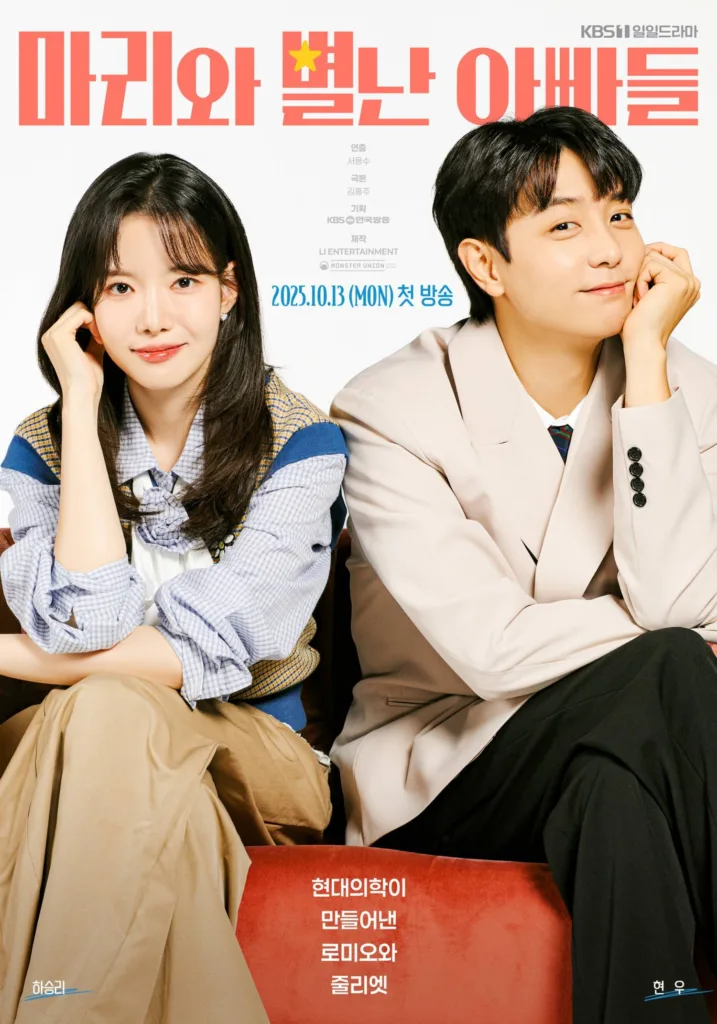 A young woman and man sit side by side on a red sofa against a clean white background, both smiling softly with their chins resting in their hands — mirroring each other’s pose in a sweet, synchronized moment. The woman, identified as Ha Seung-ri, wears a stylish blue-and-white checkered blouse layered over a white top, paired with tan wide-leg pants. The man, identified as Hyun Woo, is dressed in a light beige blazer over a collared shirt with a patterned tie, exuding gentle charm. The title “마리와 별난 아빠들” is displayed in bold coral-red letters at the top, with a small yellow star replacing the dot in “별난.” Korean text at the bottom reads: “현대의학이 만들어낸 로미오와 줄리엣” (“Romeo and Juliet, created by modern medicine”) — hinting at a love story born from unexpected circumstances. Broadcast info: “2025.10.13 (MON) 첫 방송” (First aired Oct 13, 2025, Monday). The mood is warm, playful, and heartwarming — suggesting a lighthearted romance with a touch of whimsy and family dynamics. from the best Korean dramas to watch in 2025 and beyond.