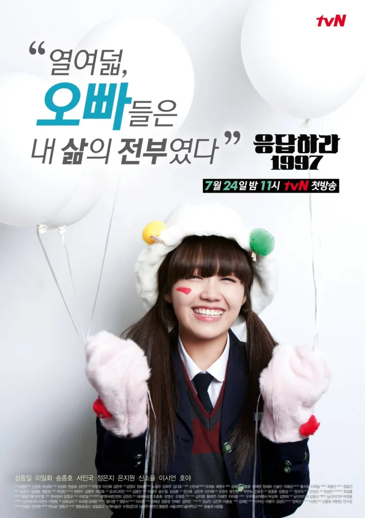 A young woman with long dark hair and bangs beams with pure joy, her eyes crinkled in a wide smile as she holds strings attached to several white balloons floating behind her. She wears a navy school uniform with a red-and-gray sweater vest, a fluffy white hat adorned with colorful pom-poms, and pink fuzzy mittens. A bright red heart is painted on her right cheek, adding to her playful, carefree vibe. The title “응답하라 1997” is displayed in bold black letters to the right, while the quote above reads: “열여덟, 오빠들은 내 삶의 전부였다” (“At eighteen, my oppas were my entire life”). The background is clean white, emphasizing her vibrant presence. Cast includes Jung Eun-ji, Seo In-guk, and Song Jong-ho. The mood is nostalgic, bubbly, and deeply affectionate — capturing the spirit of teenage fandom, first love, and the unforgettable chaos of being 18 in 1997. Replay 1997 part of the best high school k-dramas guide.