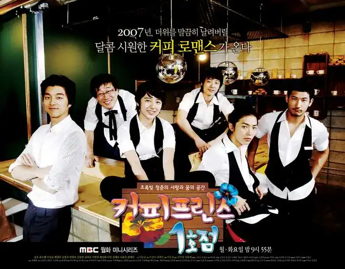 Six young adults — five men and one woman — pose playfully in a cozy, warmly lit coffee shop with wooden counters, shelves of mugs, and hanging disco balls adding a quirky, retro flair. The woman, dressed in a white shirt and black vest like the others, sits confidently on the counter, smiling brightly. Around her, the men strike relaxed, charming poses — some leaning, some grinning — all wearing matching waiter uniforms of white shirts and black vests. Korean text above reads: “2007년, 더위를 말끔히 날려버릴 달콤 시원한 커피 로맨스가 온다” (“In 2007, a sweet, refreshing coffee romance is coming to blow away the summer heat”). The title “커피프린스 1호점” is displayed in colorful, playful lettering at the bottom, with a blue flower graphic. Tagline: “초록빛 청춘의 사랑과 꿈의 공간” (“A space of green-hued youth, love, and dreams”). Cast includes Yoon Eun-hye, Gong Yoo, Lee Sun-kyun, Chae Jung-an, Kim Jae-won, and Choi Daniel. The mood is warm, lighthearted, and full of youthful charm — promising a classic rom-com about mistaken identities, friendship, and finding love in the most unexpected places. This is a promotional poster of a korean drama part of the best food-themed k-dramas.
