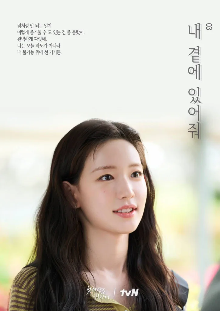 A young woman with long, wavy dark hair and a soft, radiant smile gazes thoughtfully to the side, her expression calm yet filled with quiet determination. She wears a striped green-and-brown top, and natural light highlights her features against a softly blurred background of warm outdoor tones. Korean text on the left reads: “맘처럼 안 되는 일이 이렇게 즐거울 수 도 있는 건 줄 몰랐어. 완벽하게 짜릿해. 나는 오늘 파도가 아니라 내 불가능 위에 선 거거든.” (“I never knew things that don’t go as planned could feel this joyful. It’s perfectly thrilling. I’m not today’s wave — I’m standing atop my own impossibility.”). On the right, vertical text says: “내 곁에 있어줘” (“Stay by my side”). The show’s title and “tvN” logo appear subtly at the bottom. The mood is tender, empowering, and introspective — suggesting a story of personal growth, embracing imperfection, and finding love in unexpected places. Promotional poster for the tvN drama Love, Take Two.