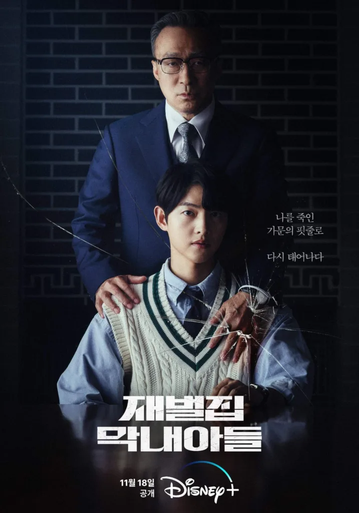 Promotional poster for the Disney+ Korean drama “재벌집 막내아들” (Jaebuljip Maknae Adeul / The Youngest Son of a Conglomerate Family), premiering November 18. A young man in a school uniform — light blue shirt, navy tie, and cream cable-knit sweater vest — sits solemnly at a table, staring directly at the viewer with a serious, almost haunted expression. Behind him stands an older man in a sharp navy suit and glasses, his hands resting firmly on the younger man’s shoulders — one hand appears to be gripping or controlling him. A shattered glass effect overlays the image, radiating from the older man’s hand, symbolizing broken trust, violence, or fractured identity. To the right, Korean text reads: “나를 죽인 가문의 핏줄로 다시 태어나다” (“Reborn as the bloodline of the family that killed me”). The title is displayed in bold, distressed white lettering at the bottom, with the Disney+ logo and release date beneath. The mood is dark, suspenseful, and emotionally charged — hinting at revenge, reincarnation, and corporate power struggles.