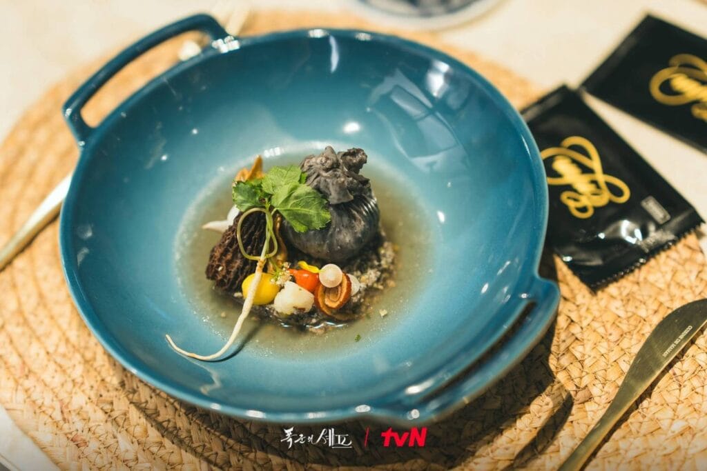 A visually striking gourmet dish from the tvN drama , Bon Appétit, Your Majesty served in a glossy cobalt-blue ceramic bowl,